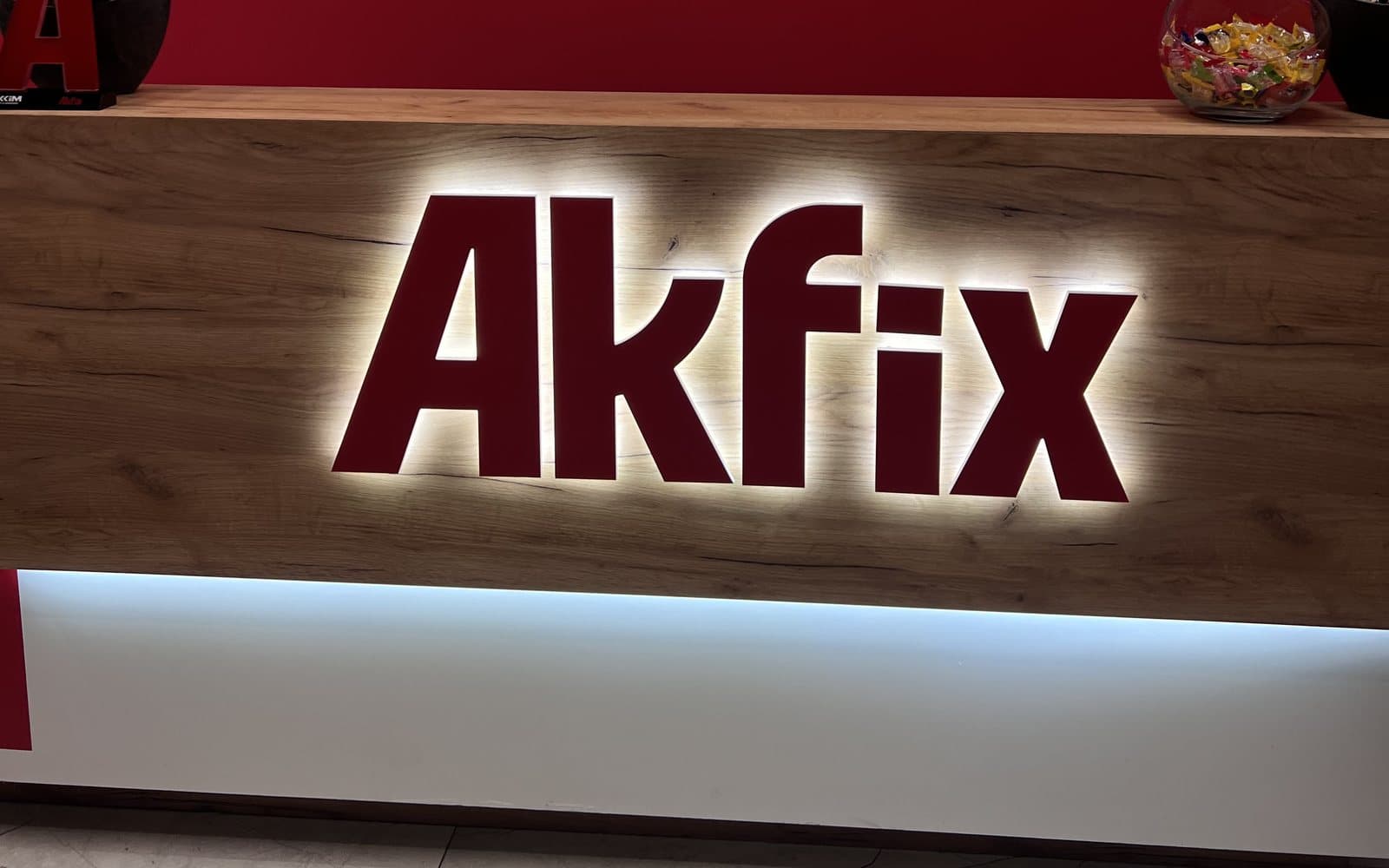 Логотип Akfix с подсветкой на деревянной стойке ресепшена