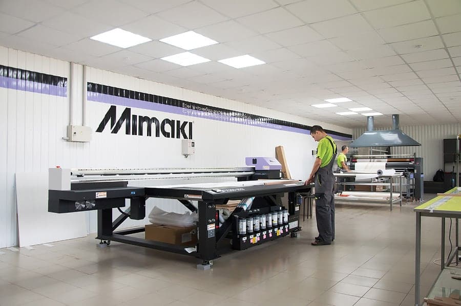 Светлый производственный цех: оператор у широкоформатного принтера Mimaki